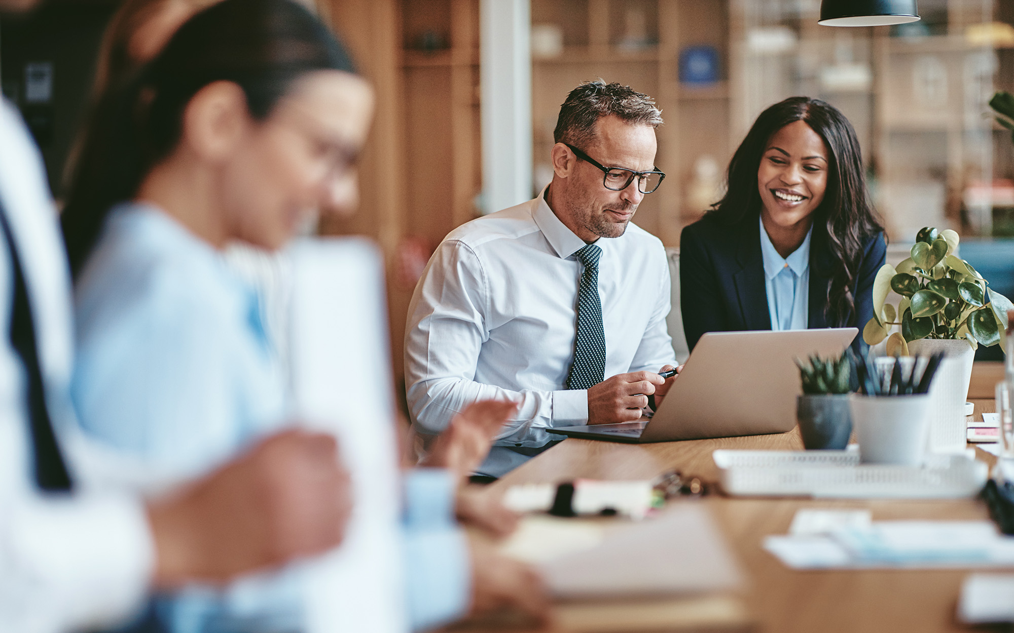Two Smiling Diverse Businesspeople Using A Laptop Together At Work
