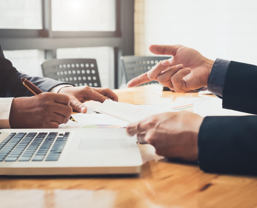 Side View Of Two Men In Suits Looking Over A Document In A Meeting