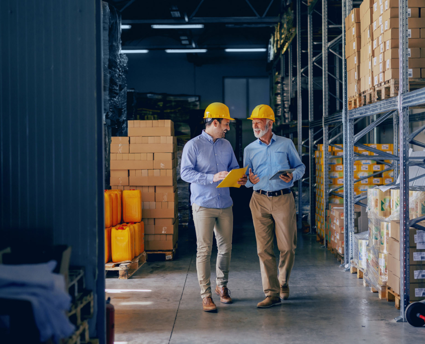 Two Business Partners In Formal Wear And With Protective Yellow Helmets