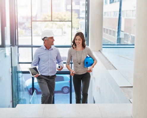 High Angle Shot Of Two Businesspeople Walking Into The Lobby Of Their Office
