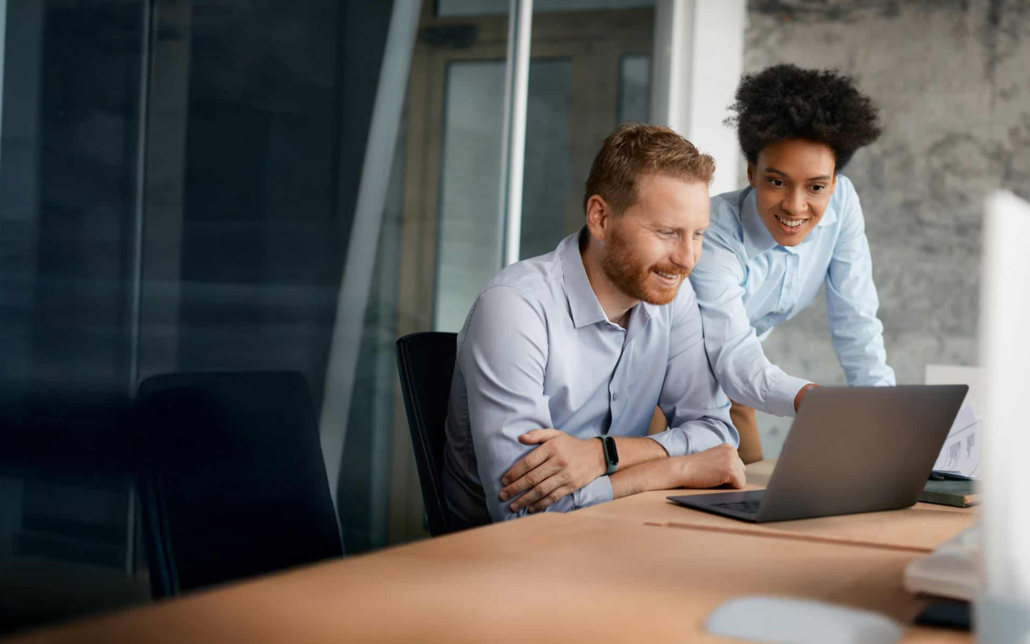Two People Gathered Around Computer Laptop